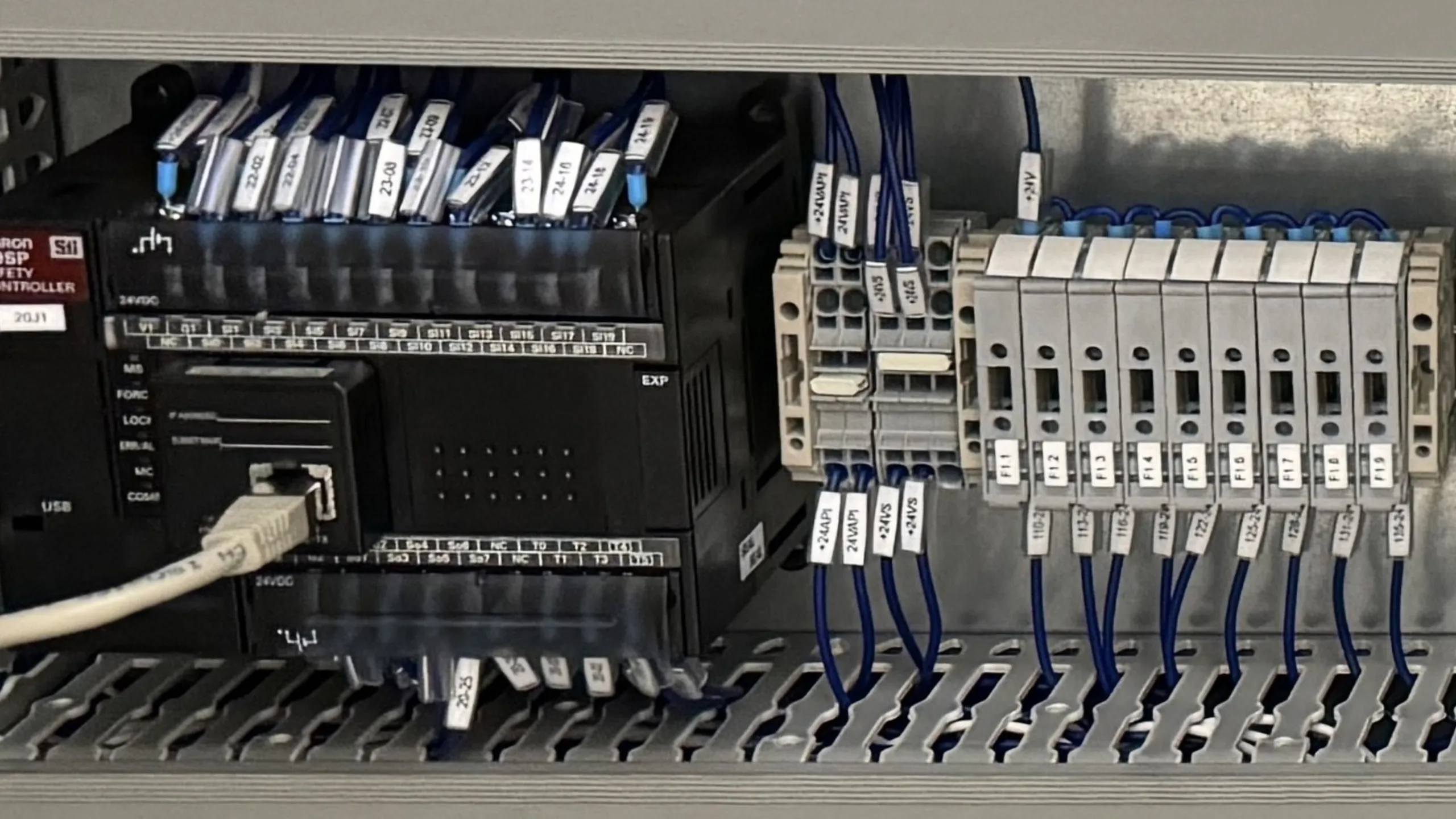 Contrôleur de sécurité Omron G9SP et bornier de distribution 24V dans une armoire électrique